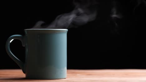 close up hot coffee cup with nature steam smoke of coffee on wooden table, black background with copy space. coffee and tea drink concept.