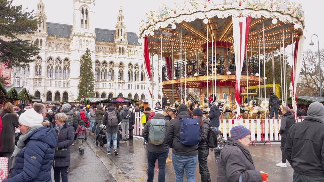 Festive carousel spinning at a busy Christmas market in front of Vienna's city hall
