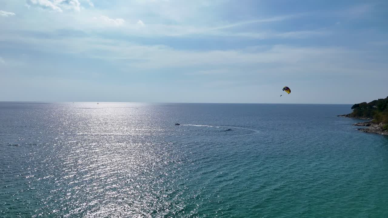 파라세일러가 태국 푸켓의 반이는 바다 위를 날아다니며 은 하늘 아래 평화롭고 모험적인 장면을 만니다.
