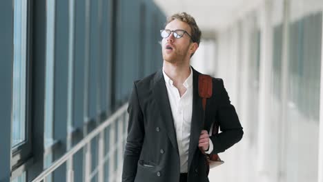 cute stylish man smokes an electronic cigarette walking down the hall