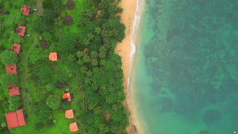 aerial view over the african coast over a resort with several bungalows and the waves breaking, inhame,sao tome e principe,africa.