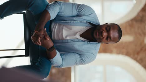 Vertical-video-of-a-Black-man-in-a-blue-shirt-talking-about-his-problem-during-group-therapy-in-a-brick-building