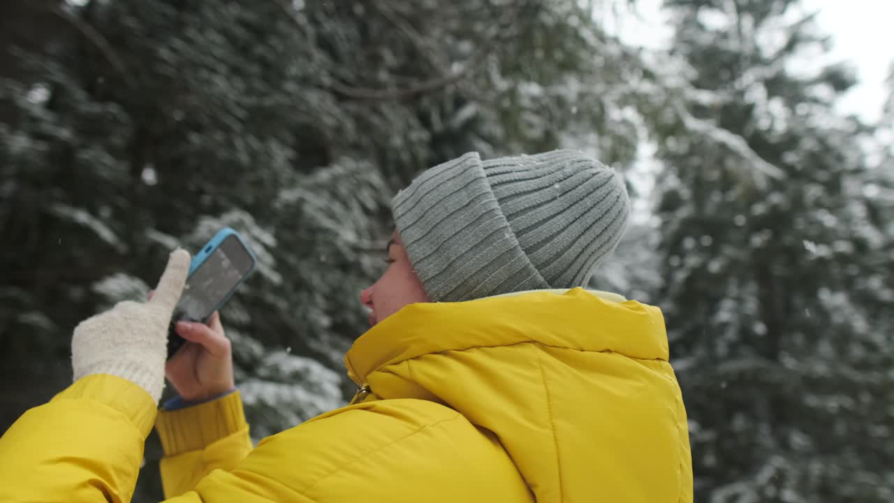 Donna che scatta foto in un bosco innevato