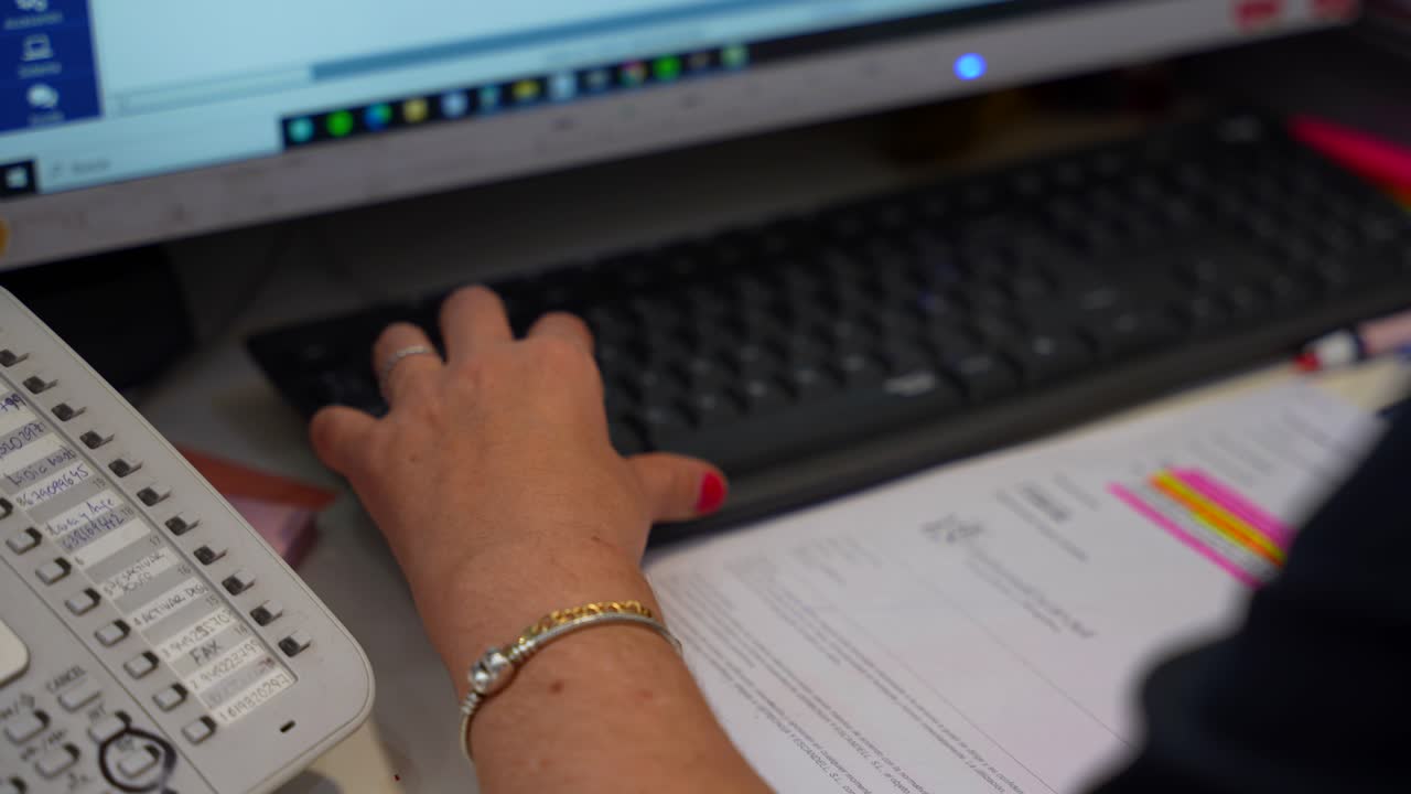 primer plano de la mano de una recepcionista con pulseras trabajando en una computadora en una clínica dental