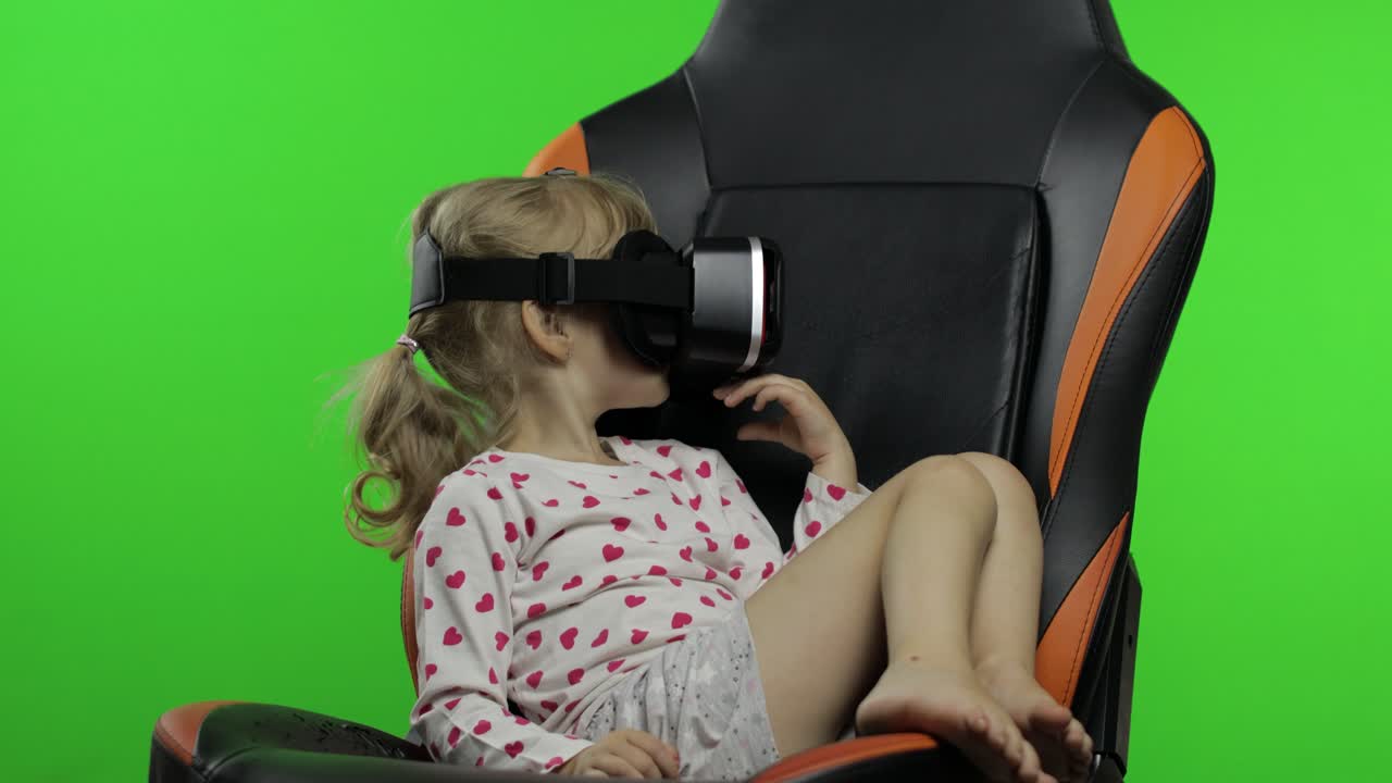 Child girl using VR headset helmet to play game. Watching virtual reality 3d 360 video. Chroma key