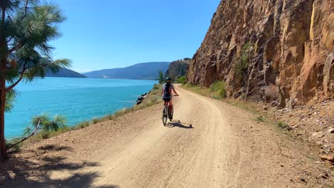 woman riding bike along beautiful lake side trail