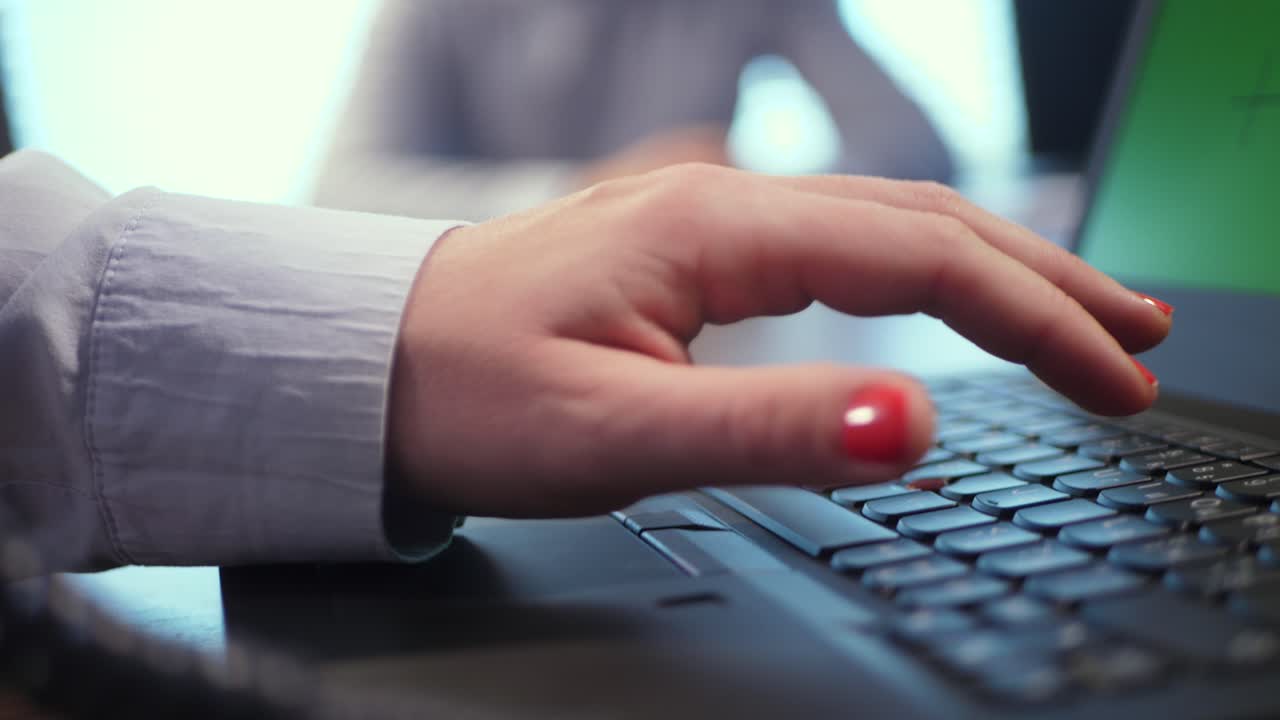 A female hand types a password on a laptop keyboard, dictated to her