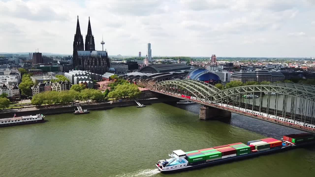 Drone shot of a cargo boat crossing under the Bridge in Cologne (Köln) with the city as the backdrop scenery, Germany.