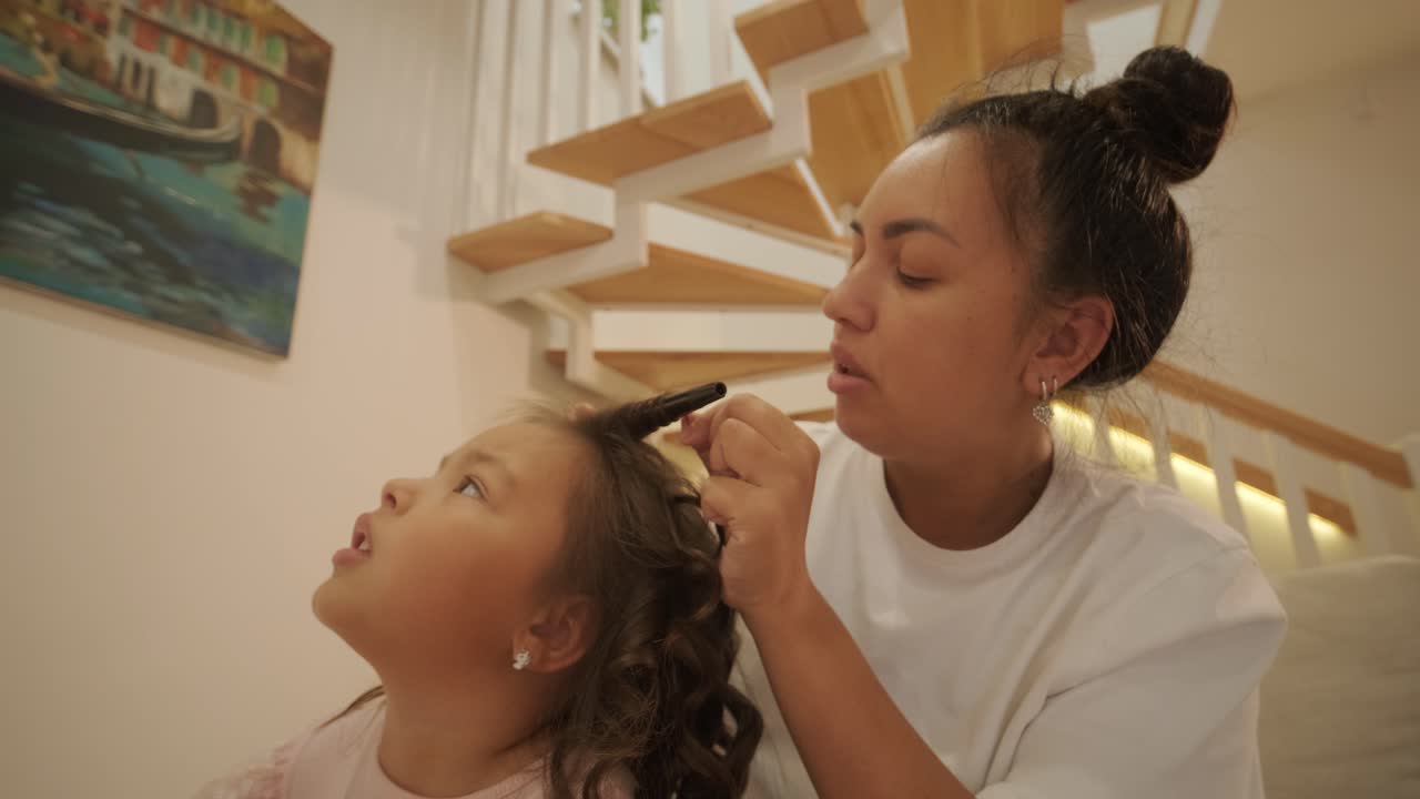 madre embarazada peinando el cabello de su hija en casa