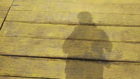 schaduw van een fotograaf die op een houten brug loopt