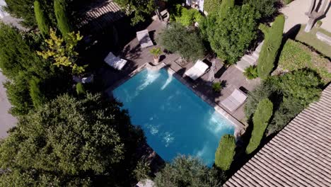 Aerial-arcing-shot-of-a-private-pool-with-sun-loungers-at-a-chateau-in-France