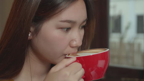 beautiful young asian girl drinking coffee at a coffee shop with a laptop