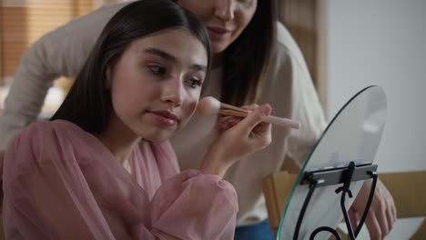 caucasian woman teaching daughter how to do make up for a prom