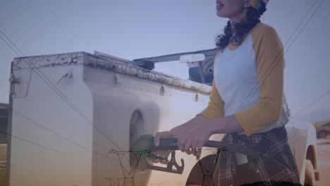 Animation-of-electricity-poles-over-caucasian-woman-refueling-car