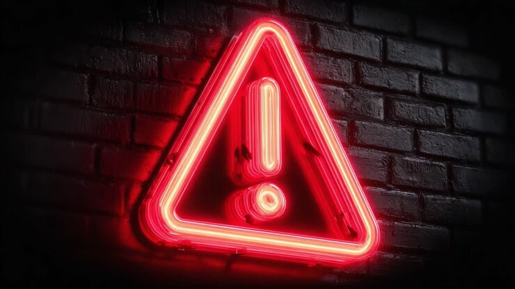 Segnale di avviso illuminato su un muro di mattoni scuri: un contrasto sorprendente di rosso neon e nero, che attira l'attenzione con il suo design audace e il simbolismo urgente di pericolo.