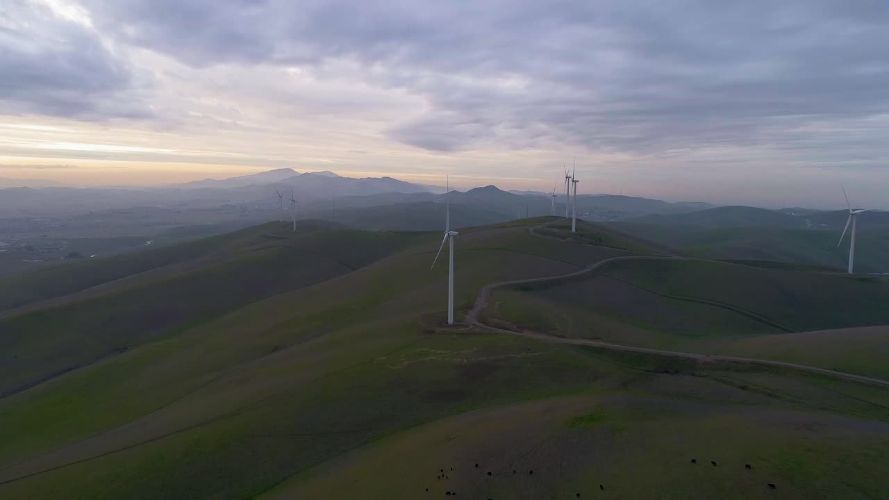 Reverse Dolly of Wind Turbines with Distant Smokey Mountain Mist and Moody Clouds at Dusk
