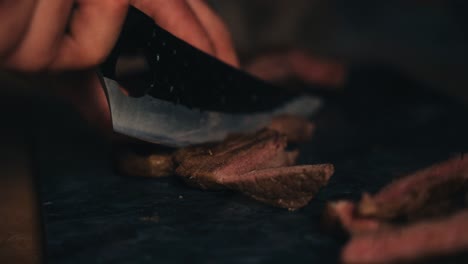 a close-up shot of hands slicing cooked meat on a cutting board in warm lighting