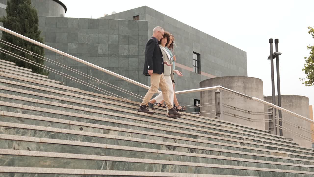 Happy business people talking while descending stairs in city