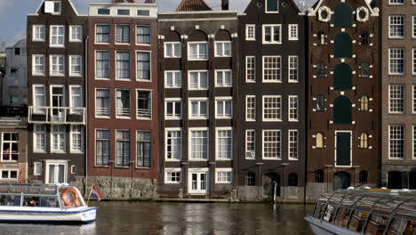 canal with taxi boat passing in amsterdam, the netherlands