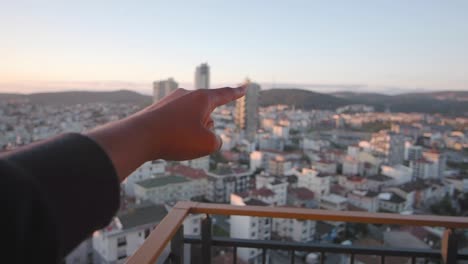 mano apuntando a una vista de la ciudad desde un balcón