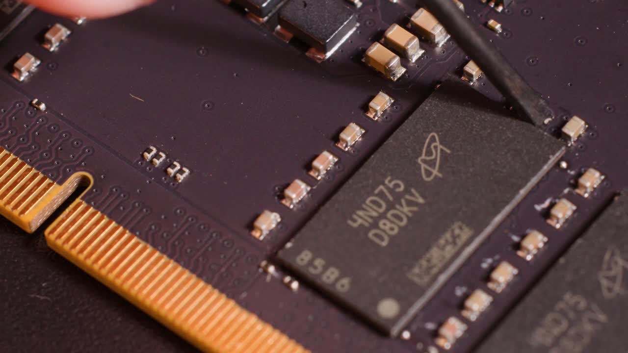 Close-up macro shot of a technician using a tool to repair a computer motherboard microchip