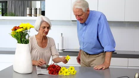 Frau-Arrangiert-Blumen-Und-Hält-Einen-Davon-An-Die-Nase-Ihres-Mannes