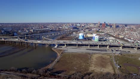 Aerial-wide-shot-where-drone-drone-pans-right-along-traffic-flowing-on-interstate-and-city-beyond