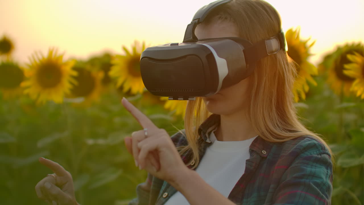 la estudiante está trabajando en gafas vr. está involucrada en el proceso de trabajo. es un día soleado perfecto en el campo de girasoles.