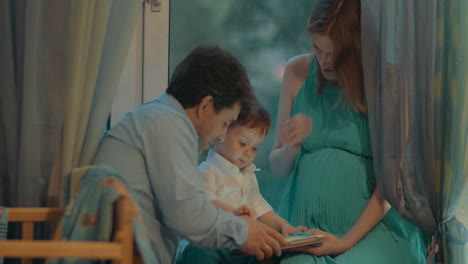 little boy holding tablet and his parents