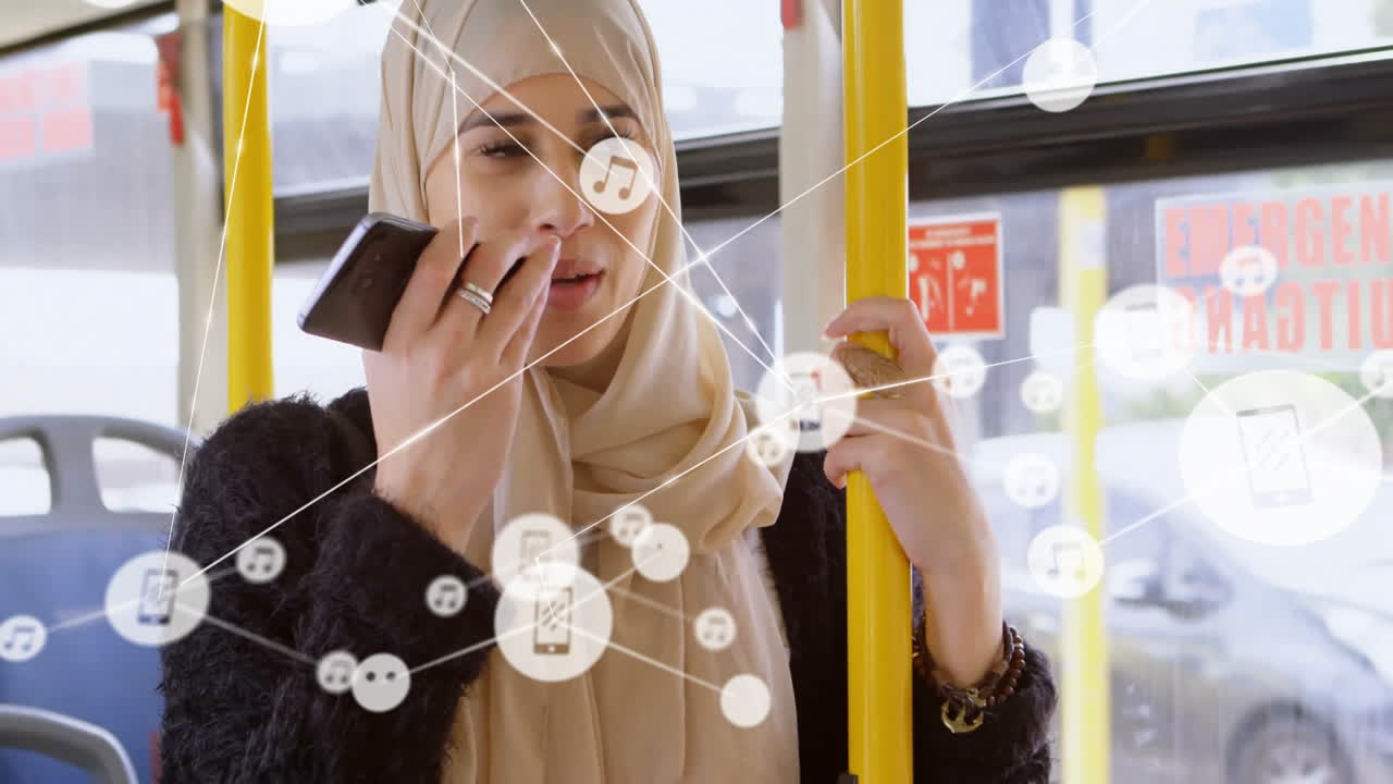 woman wearing hijab riding bus holding handrail speaking into smartphone with technology icons