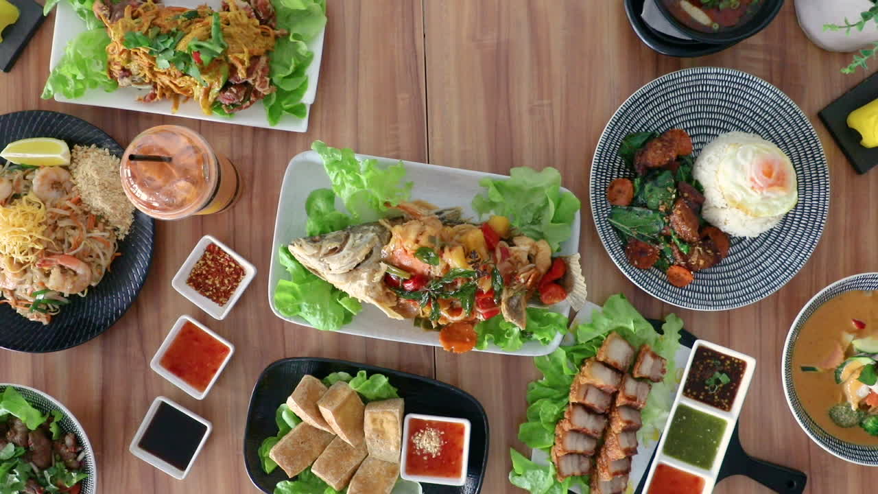 Male hand picking up thai cuisine spring roles from flat lay food arrangement