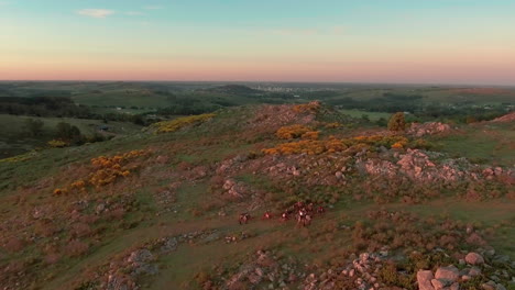 AERIAL---Gauchos-and-horses-at-sunset-near-Tandil,-Argentina,-wide-spinning-shot