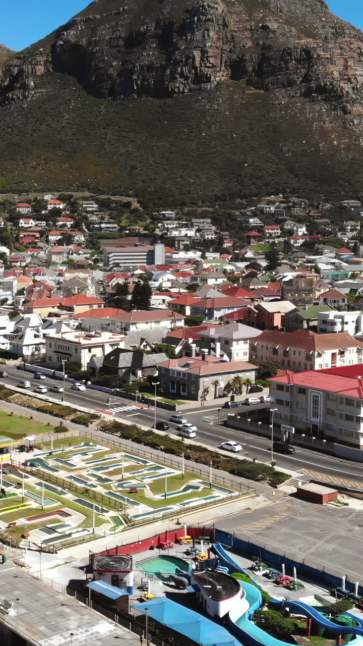 Vista aerea di una città costiera con campo da minigolf e montagna