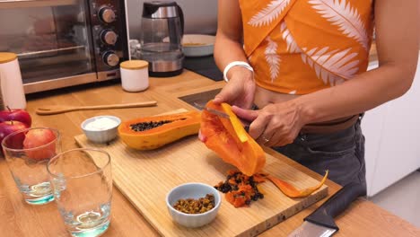 una mujer preparando una papaya.