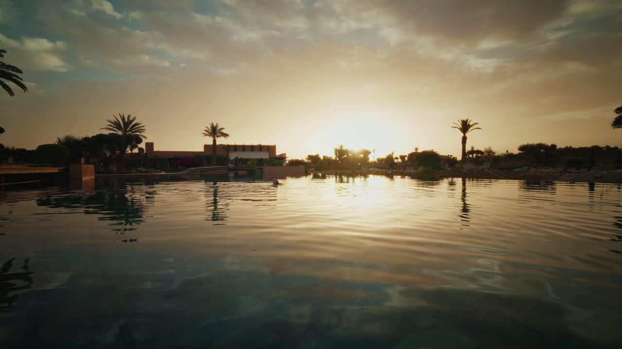 Panoramic view of the Fairmont Royal Palm Resort in Morocco at sunrise. Warm colors. The sun and sky reflecting on the water.