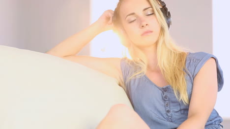 Beautiful-blonde-teen-relaxing-on-her-sofa-and-listening-to-music