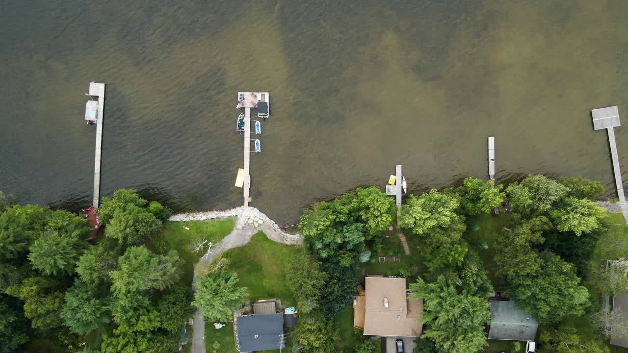 Top down bird's eye view, private docks with boats watercraft jetskis docked at lake house vacation spots