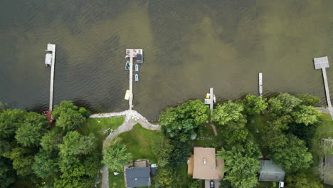 Top-down-bird's-eye-view,-private-docks-with-boats-watercraft-jetskis-docked-at-lake-house-vacation-spots