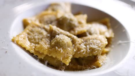 fork lifting ravioli from a cheese-covered plate