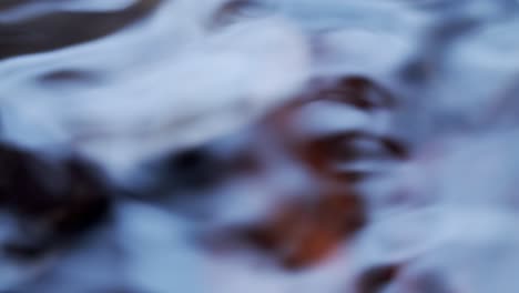 close up of water in a creek passing over some shallow leaves