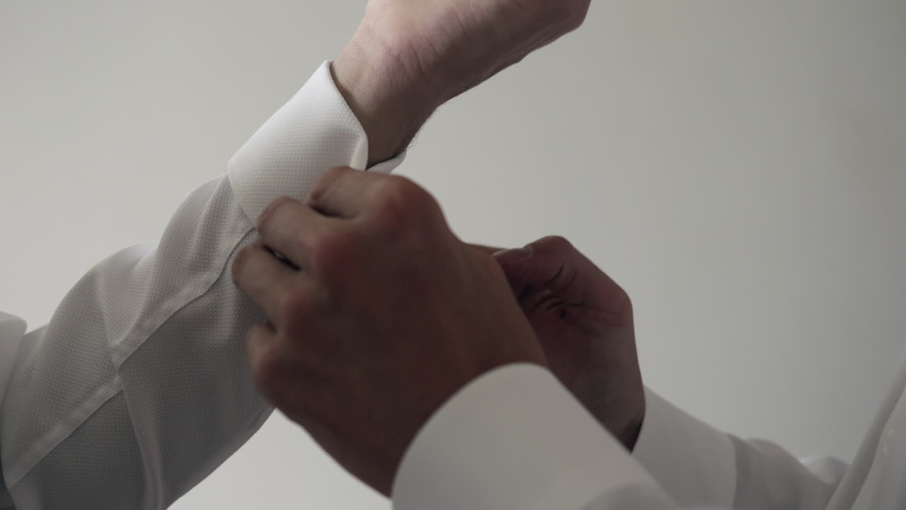 amigo masculino ayuda a hacer los botones de los puños de la camisa de manga larga, en cámara lenta