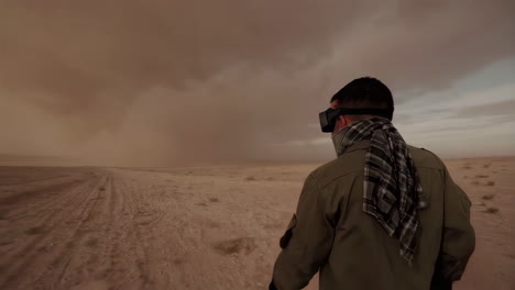 man walking through a sandstorm in the desert