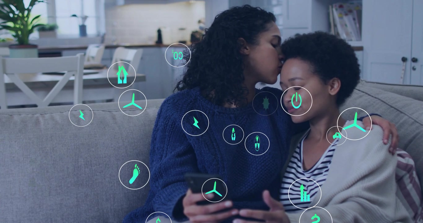Couple on sofa, left holding phone and kissing, initiating teal icons overlay, digital sharing