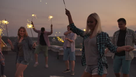 young russian girls in denim shorts beautifully move their bodies on the roof with big bengal light. this is a fun party with friends.