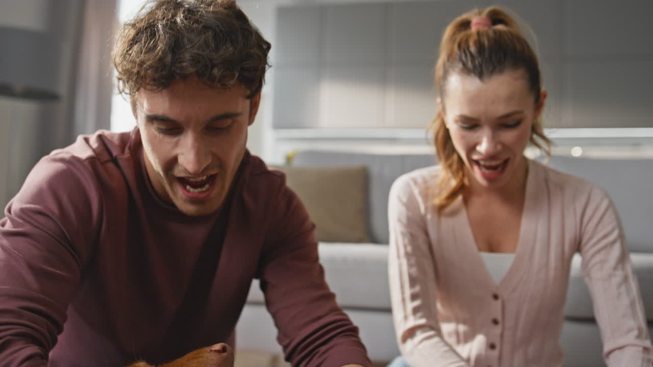 Couple hands caressing puppy lying on man knees close up. Family stroking dog