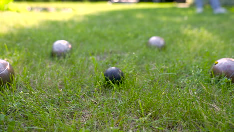 vista cercana de algunas bolas de petanca de metal en el césped del parque