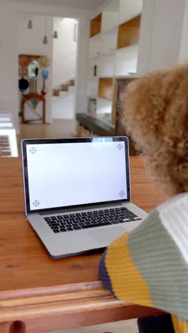 vertical video of biracial woman using laptop with copy space on screen, slow motion