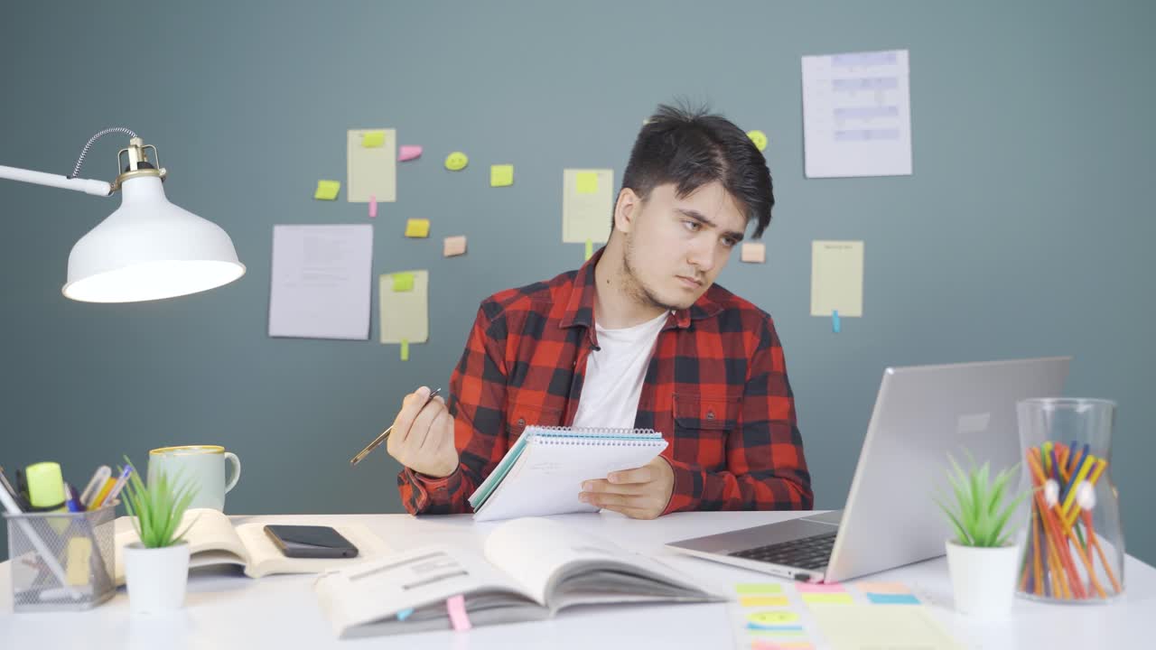 estudiante masculino trabajando entre el papel y la computadora portátil.