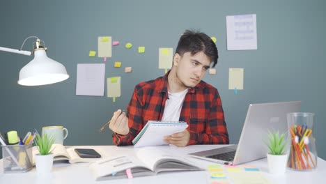 Estudiante-Varón-Trabajando-Entre-Papel-Y-Computadora-Portátil.