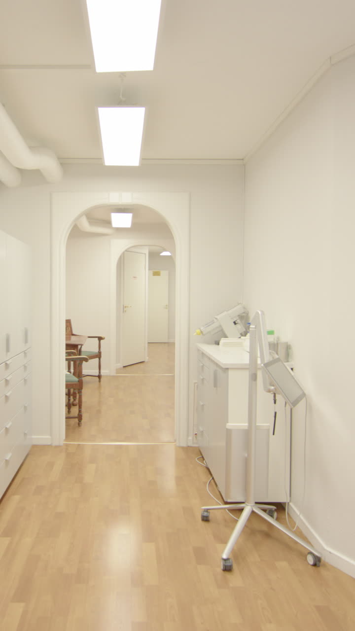 Patient POV walking down medical centre corridor into dentist's office, vertical